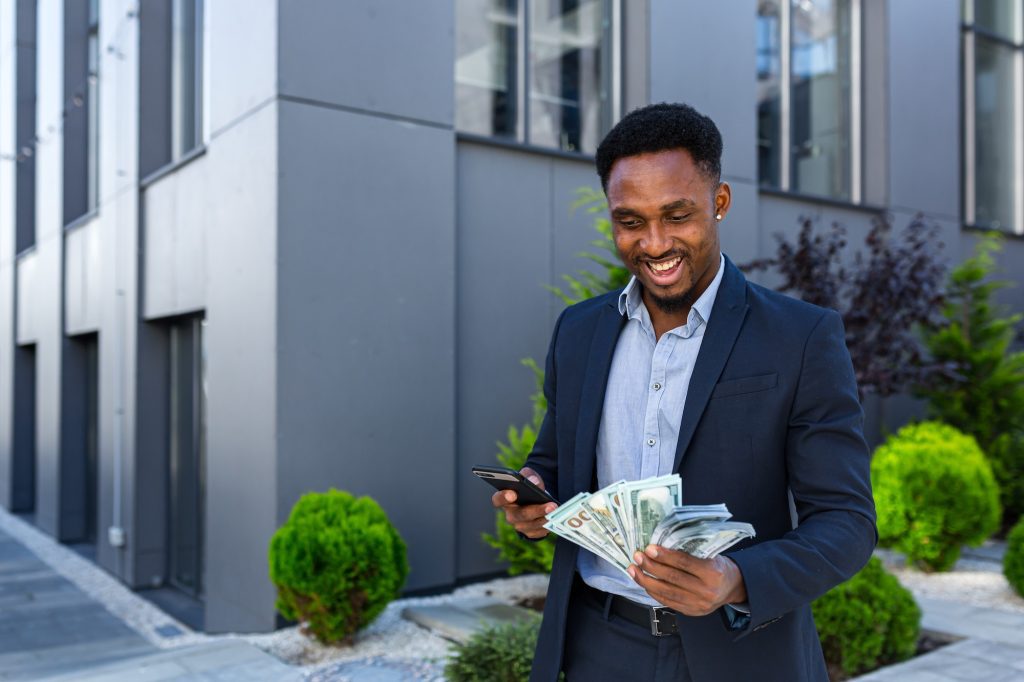 African american businessman standing on street modern building show earnings winning